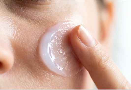 A smooth, creamy moisturizer being applied to the cheek with a fingertip
